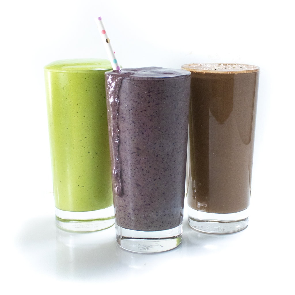 An image of three clear glasses with three different variations of a pregnancy smoothie – one is green, one is purple and one is chocolate.