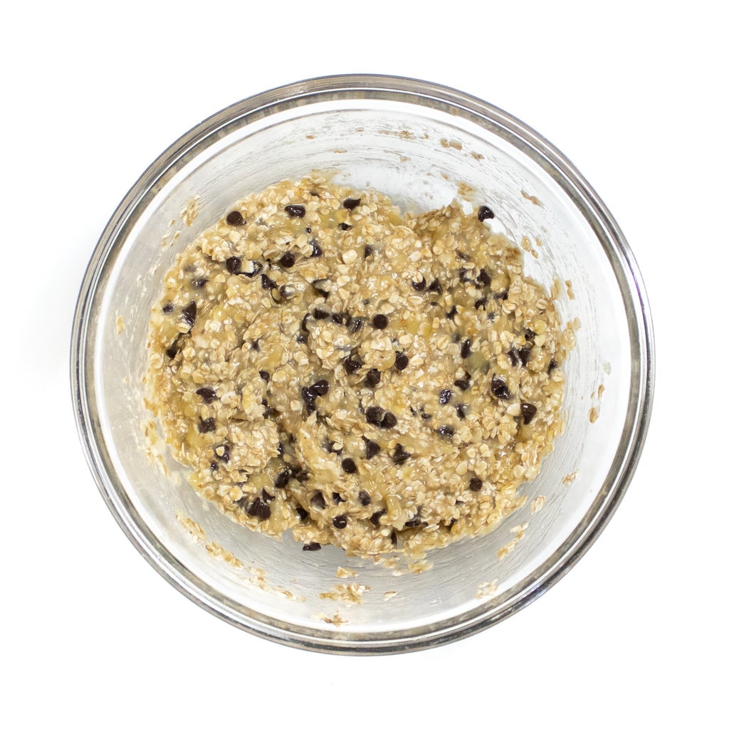 Clear bowl full of bananas, oats and chocolate chips.