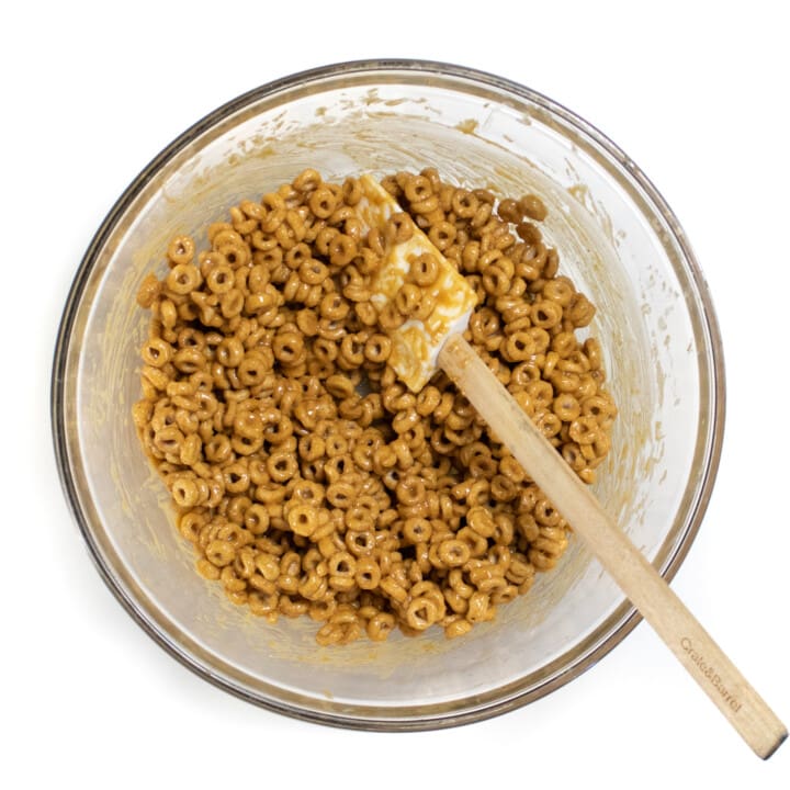 A glass bowl full of ingredients for cereal bars.
