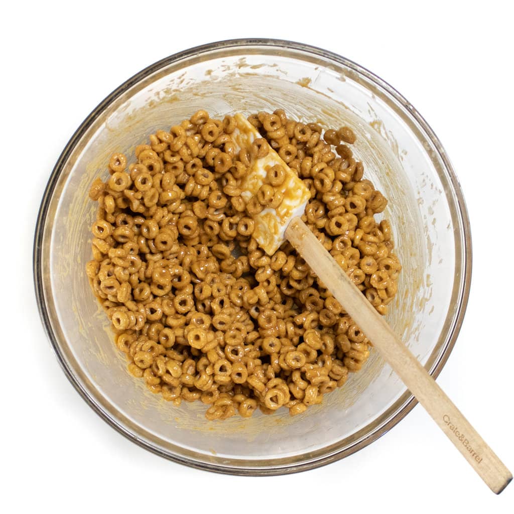 A glass bowl full of ingredients for cereal bars.