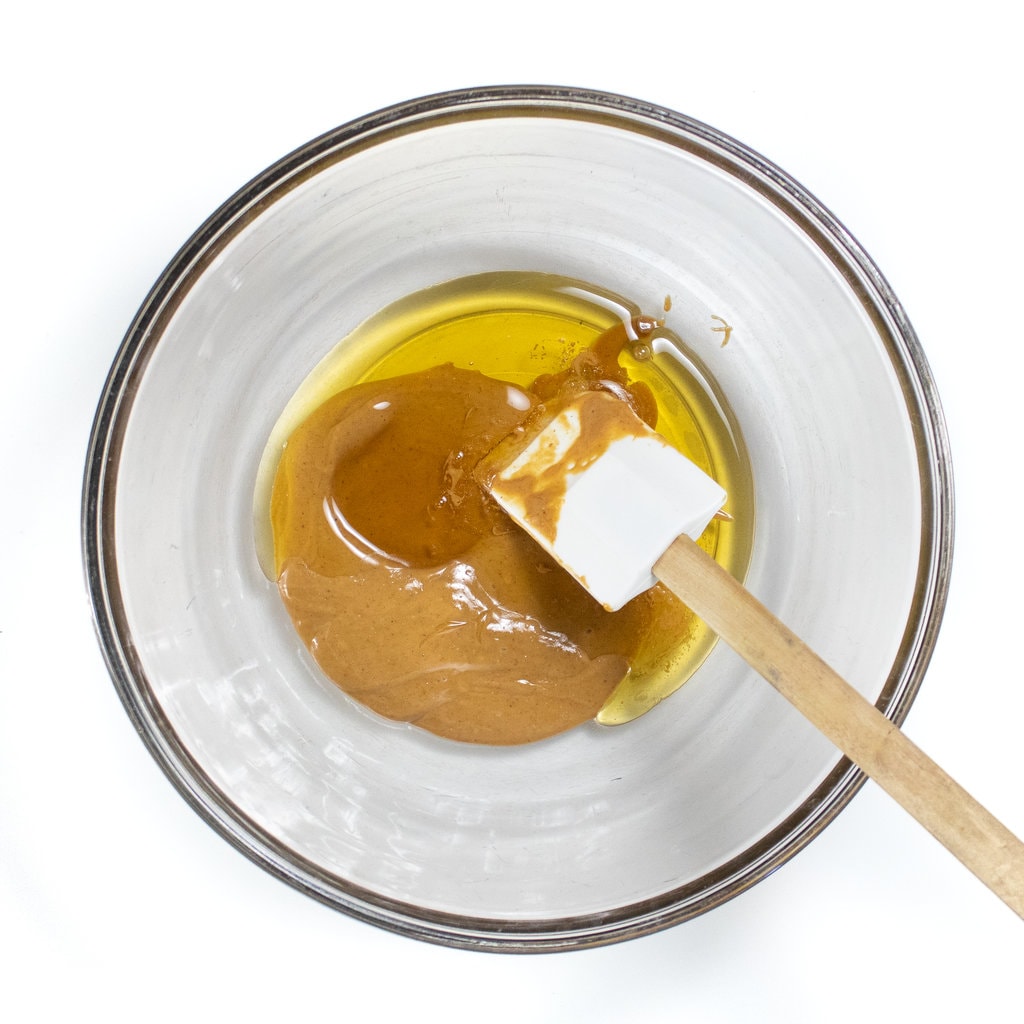 A clear glass bowl filled with peanut butter and a agave nectar about to be mixed.