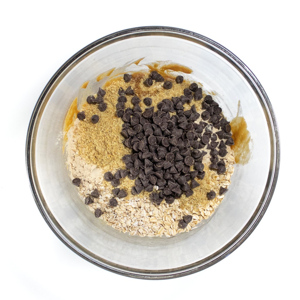 A clear glass ball against a white background with wet ingredients and dry ingredients about to get mixed together for lactation bites.