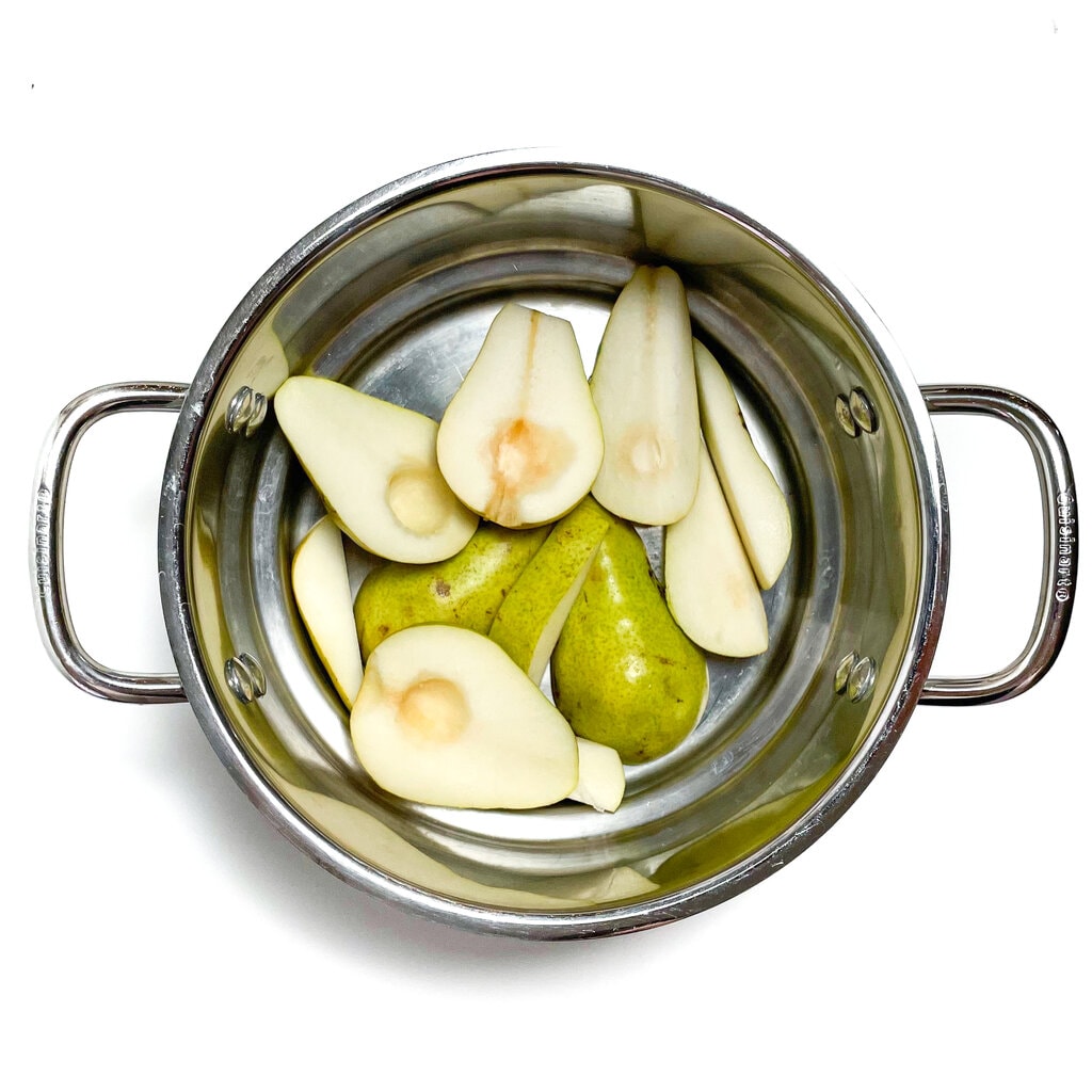 Green pears cut and in a silver steamer basket.