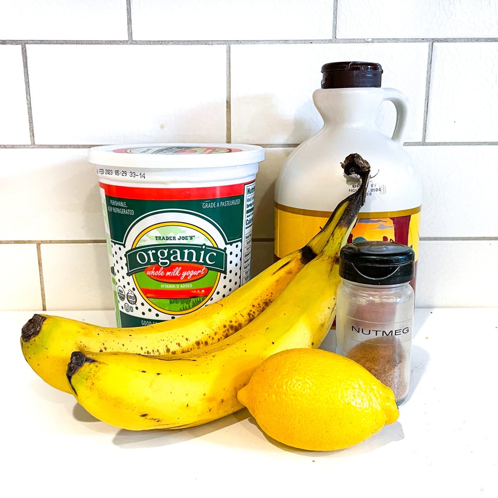 A white kitchen with ingredients for banana yogurt on it.