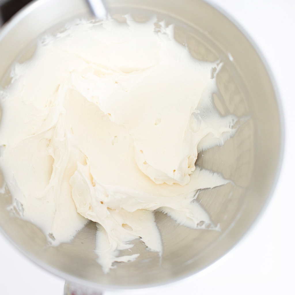 Silver mixing bowl with smooth and creamy cream cheese frosting.