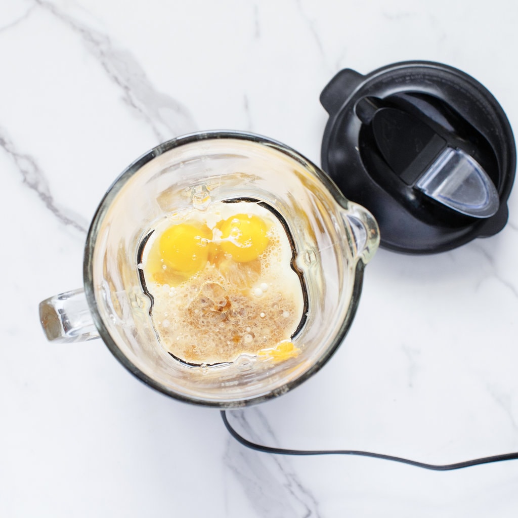 Blender on a marble counter with the lid off and the wet ingredients inside.