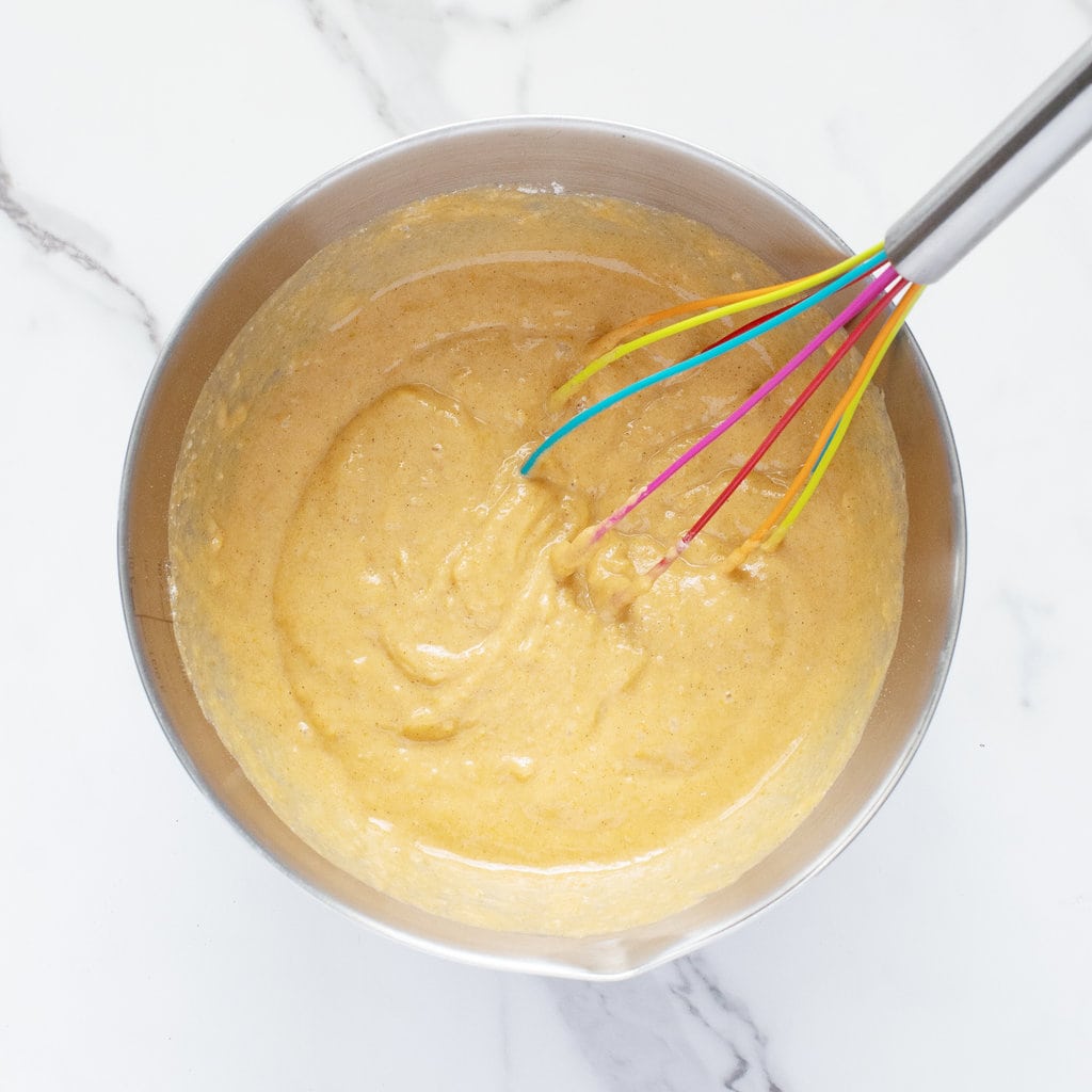 A large mixing bowl with sweet potato muffin batter inside.