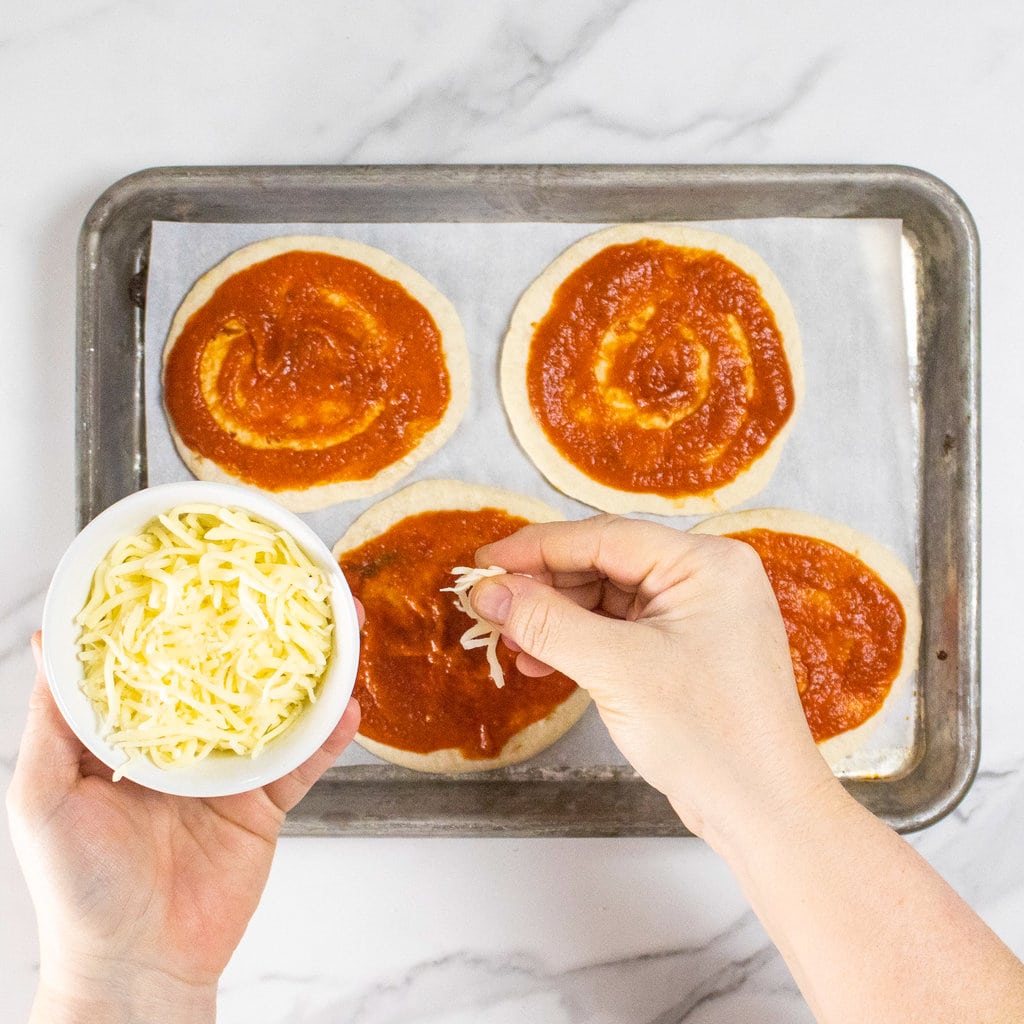 I can cheat on a marble countertop with four tortillas with pizza sauce and a hand sprinkling cheese on top.
