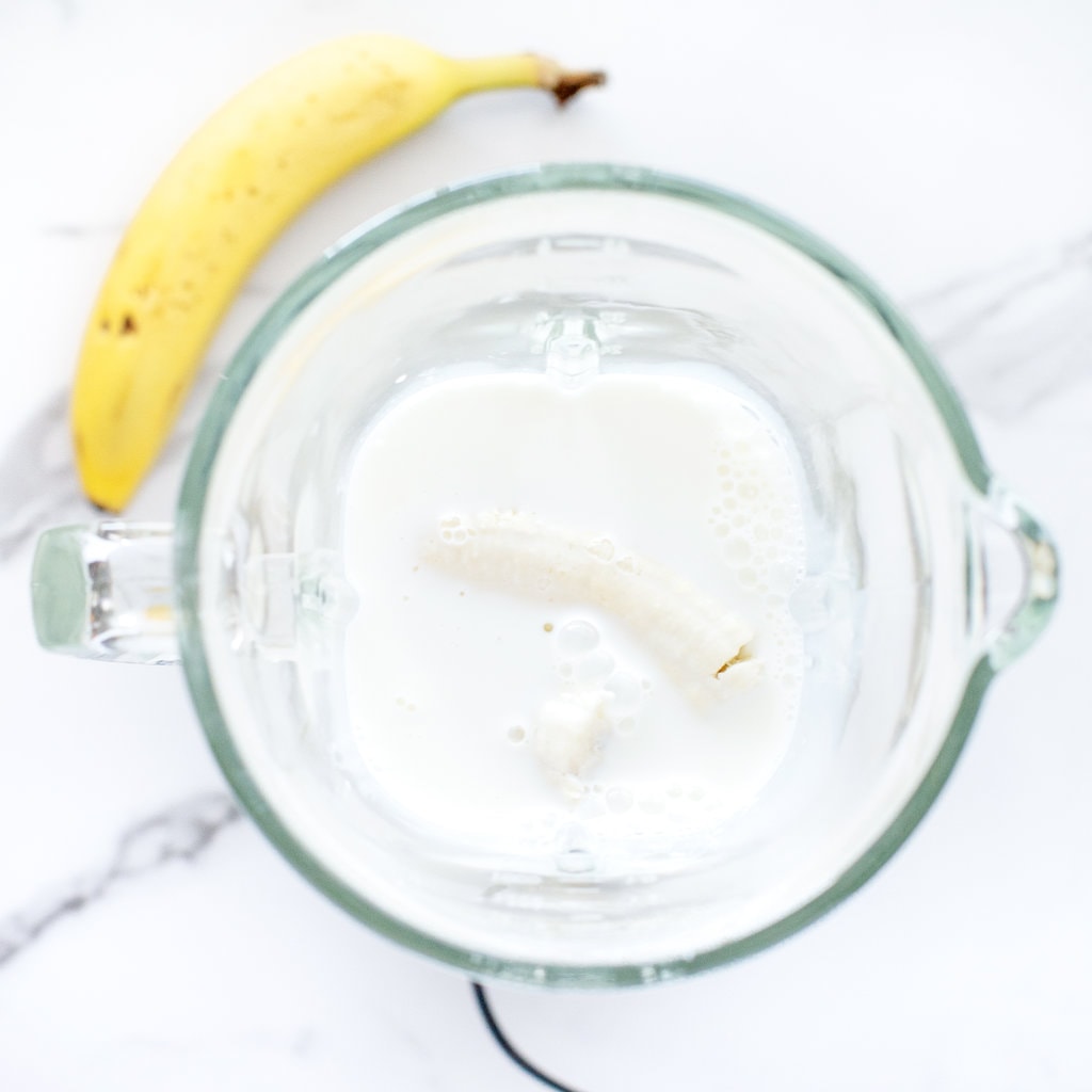 A butter full of milk, bananas and maple syrup with a banana on the side.