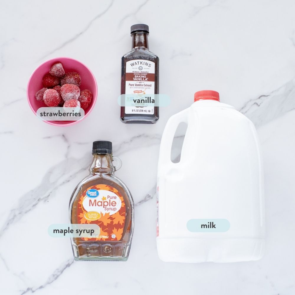 Spread of ingredients on a marble counter to make strawberry milk.