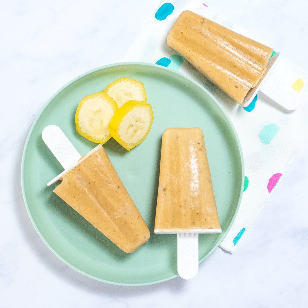 A kids teal plate with banana popsicles and slices of bananas. 