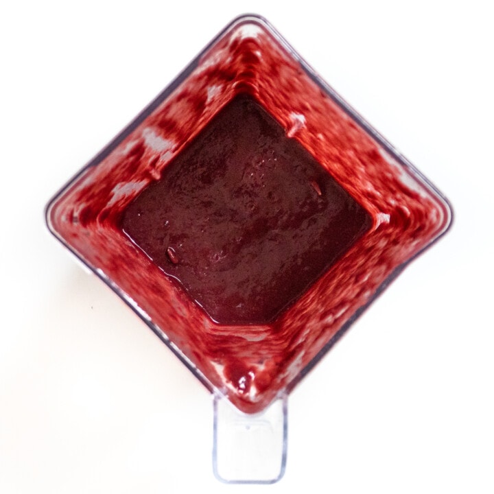 A clear blender full of blackberry puree.