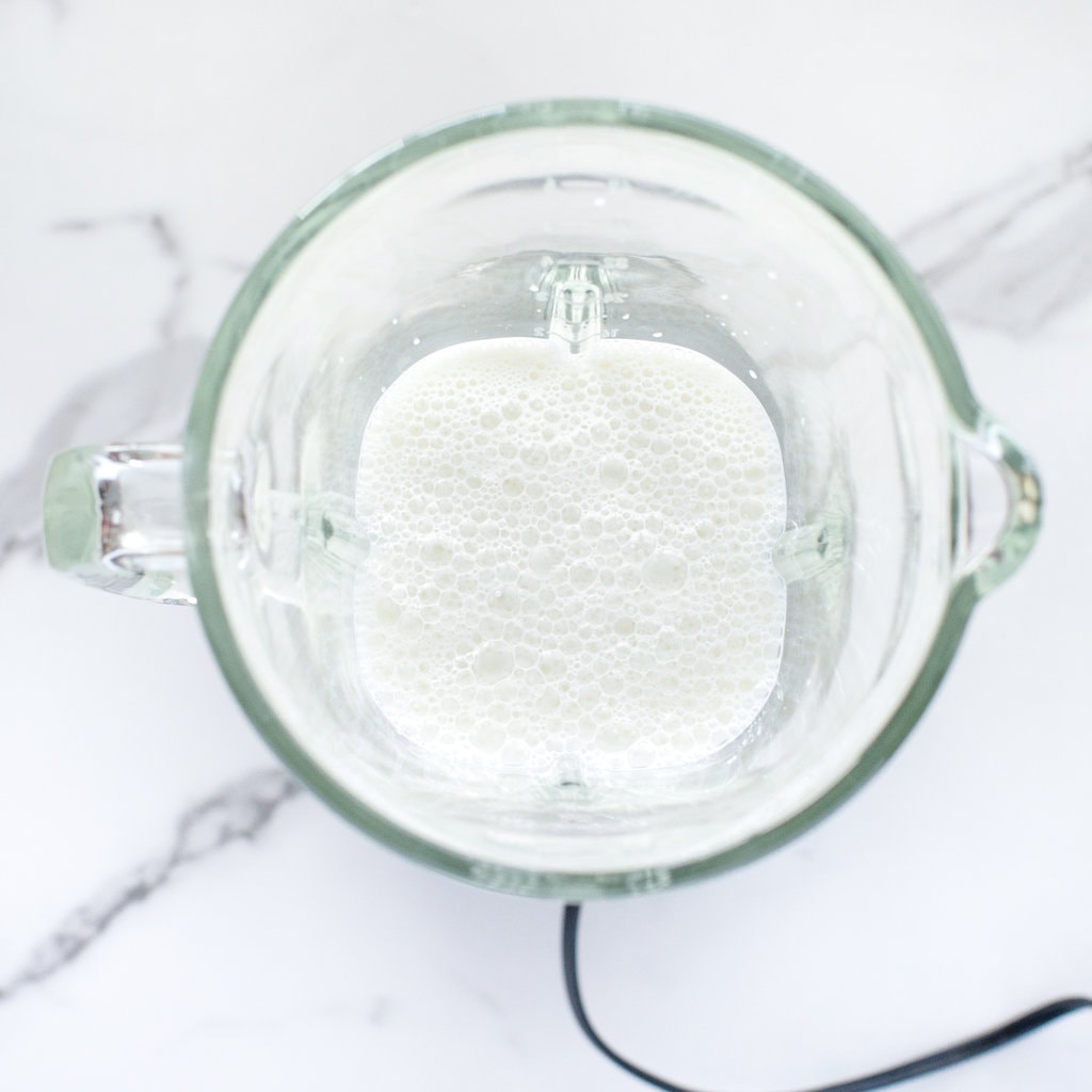 A clear blender with milk.