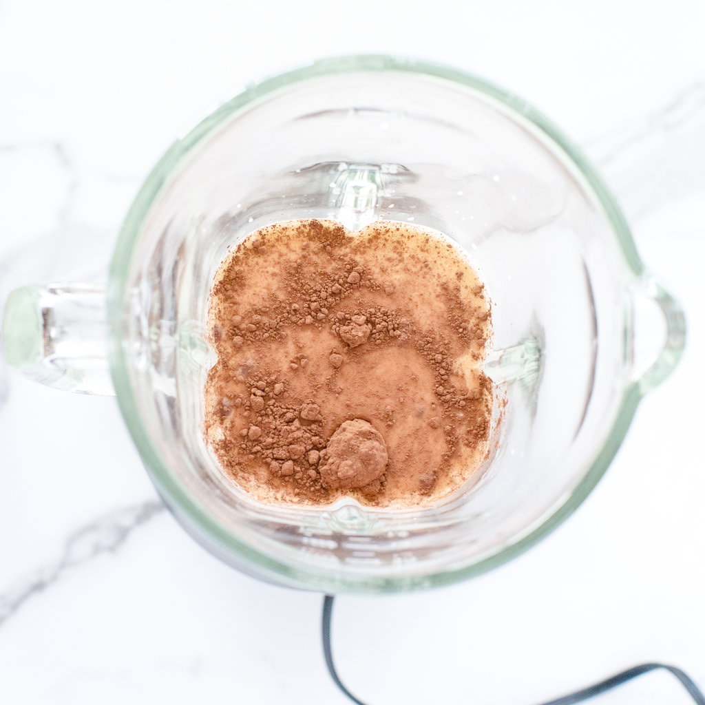 A clear blender with ingredients for homemade chocolate milk.