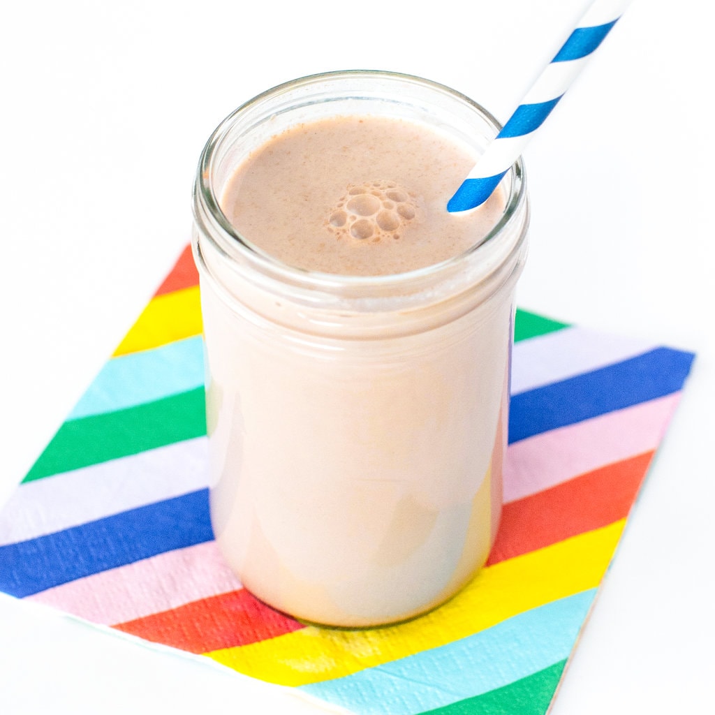 Clear glass full of chocolate milk for kids on a colorful napkin and striped job.