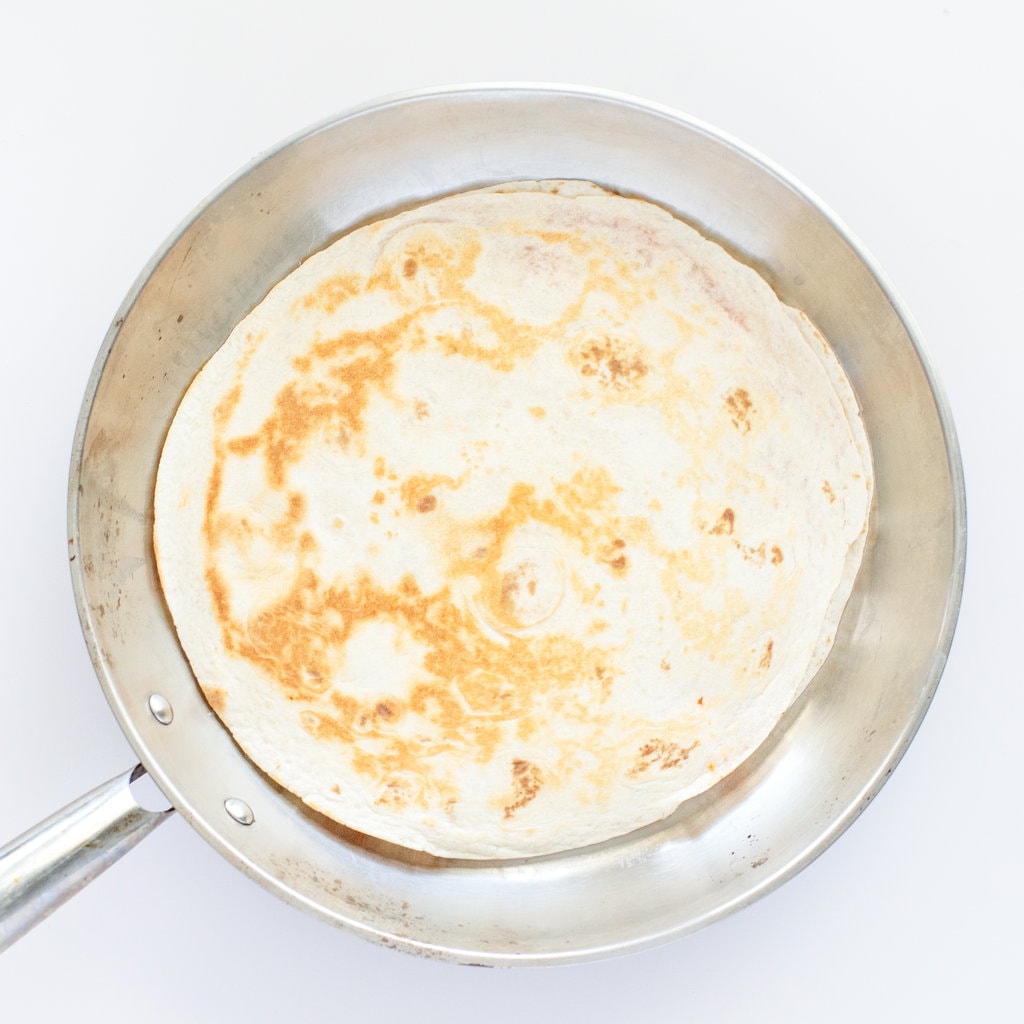 A cooked quesadilla pizza style in a silver skillet.
