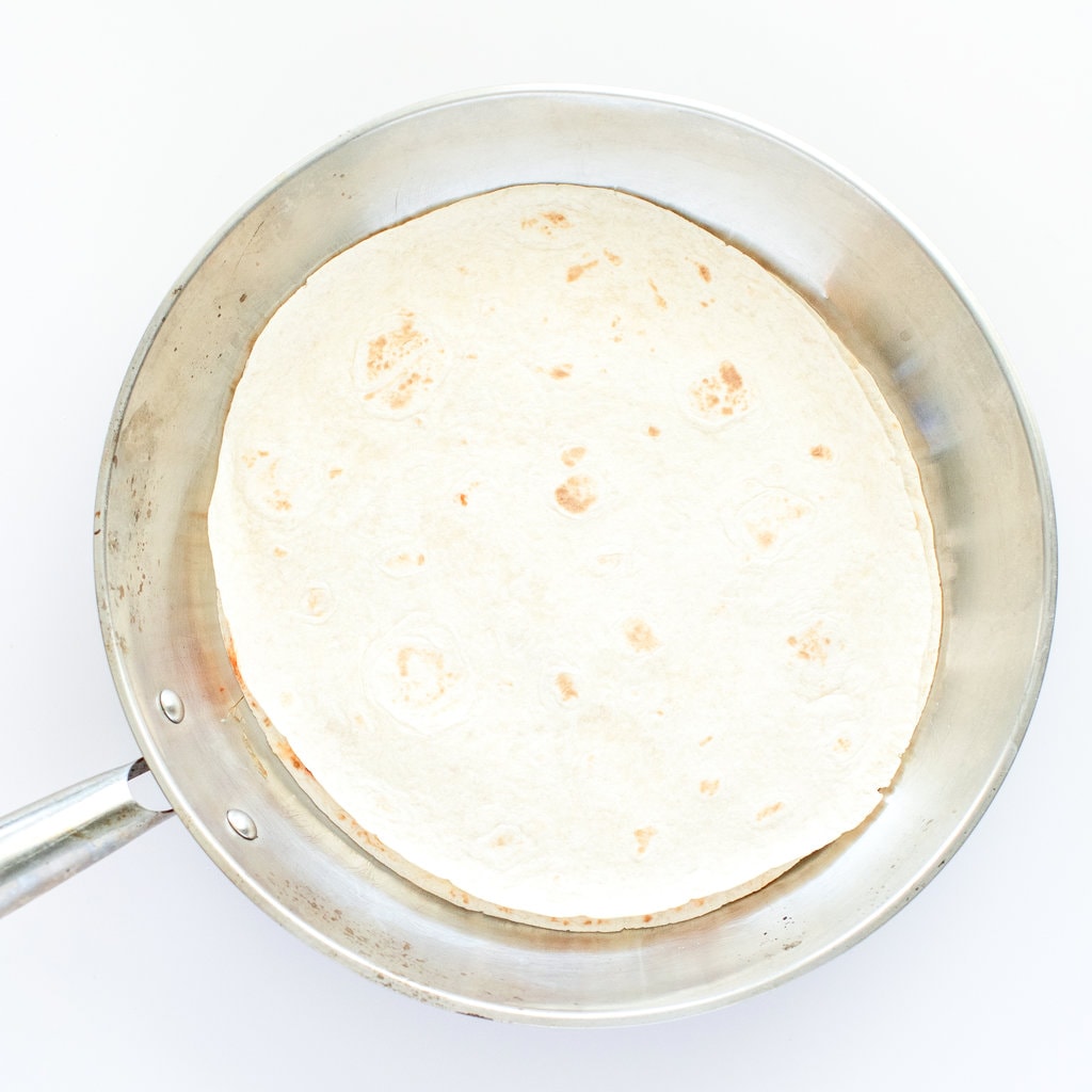 An uncooked pizza quesadilla in a silver skillet.