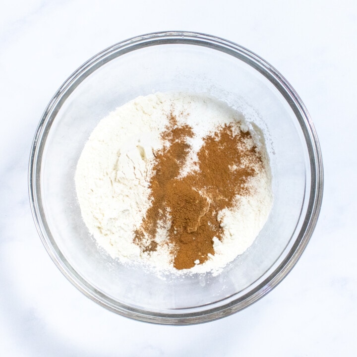 Clear bowl with dry ingredients for pancakes against a marble countertop.