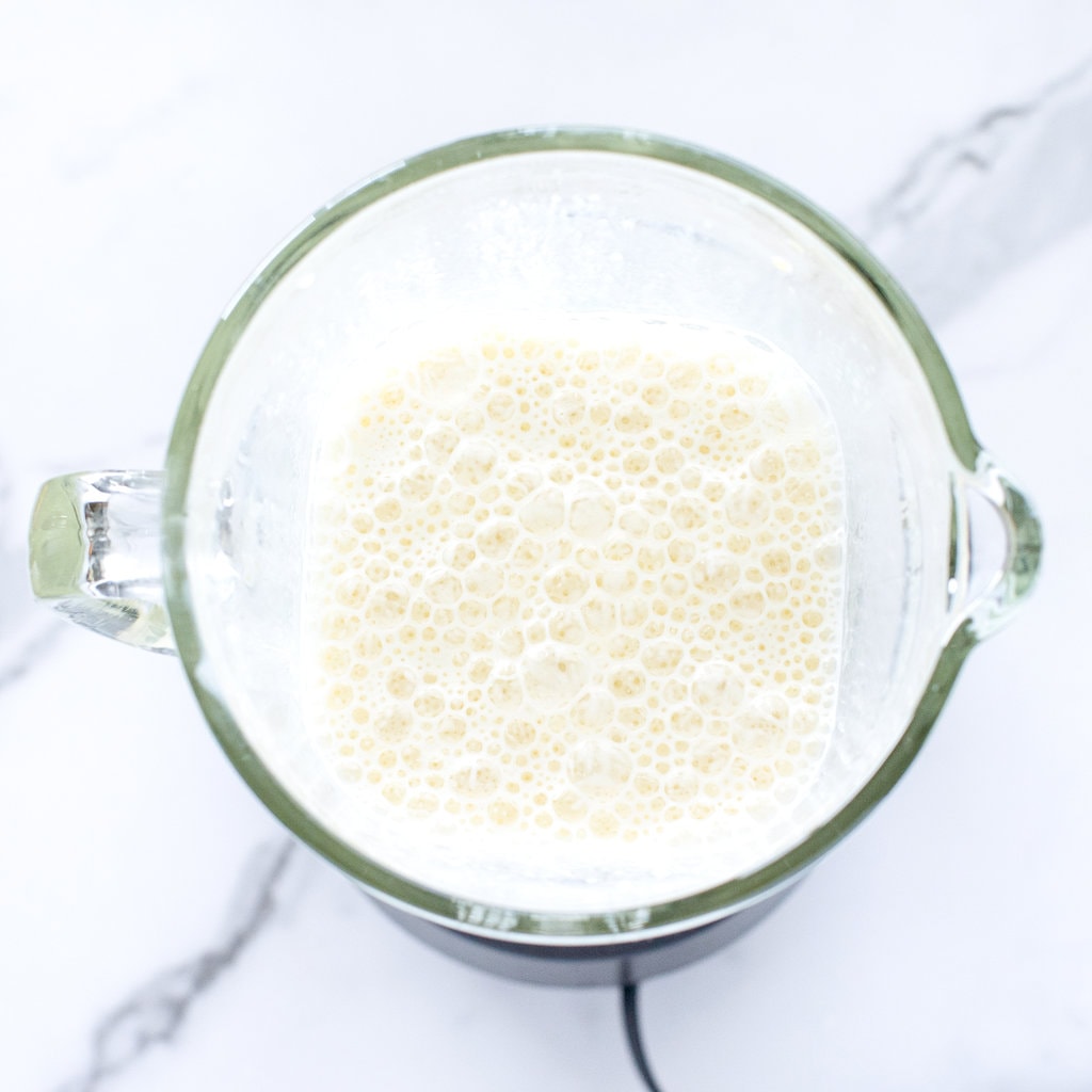 Mango milk in a clear blender against a white background.