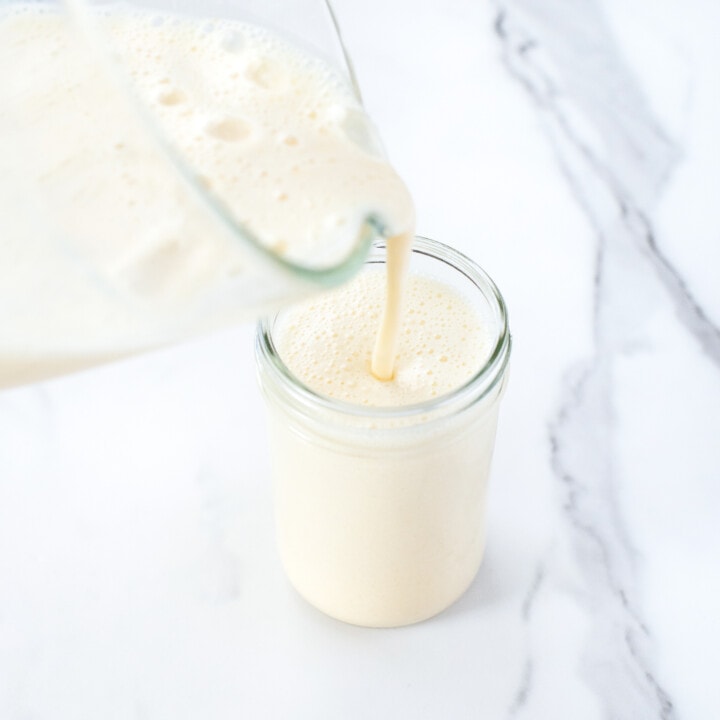 A clear blender pie mango milk into a clear glass and a marble backgrounds.