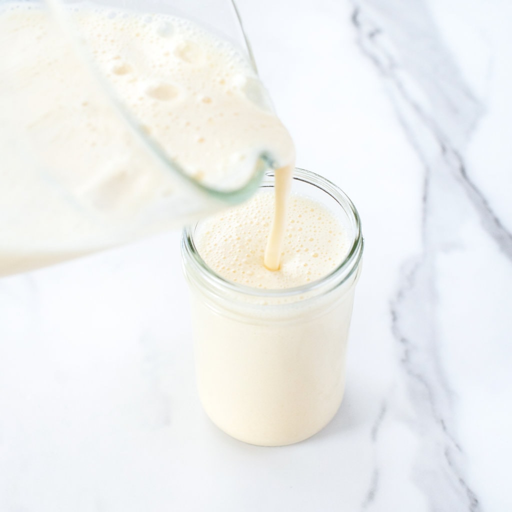A clear blender pie mango milk into a clear glass and a marble backgrounds.