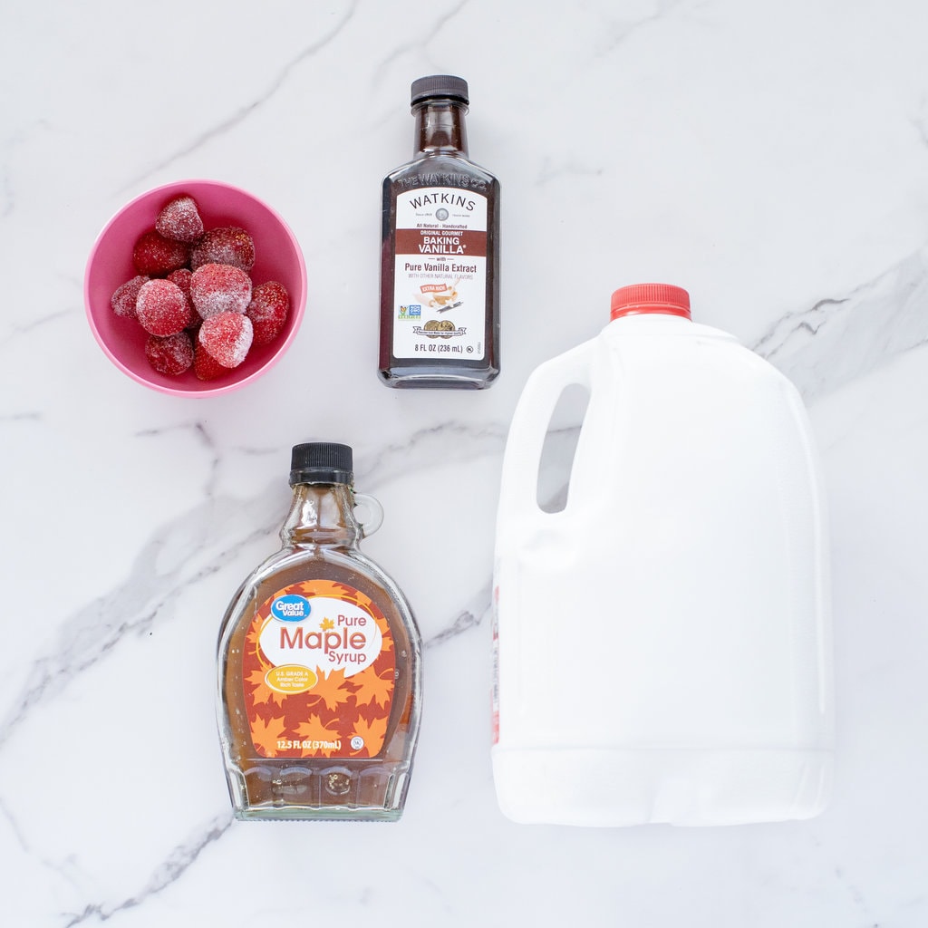 Ingredients for strawberrry milk on a marble countertop.