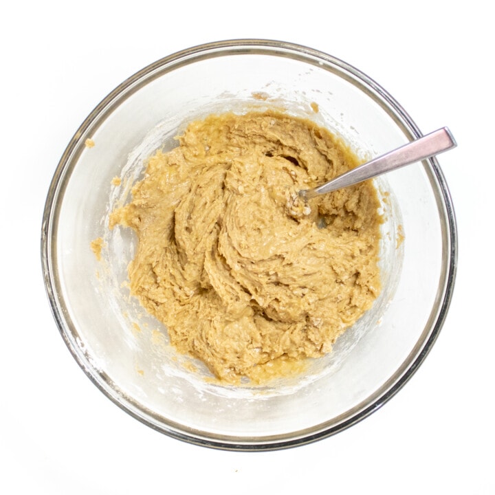 Clear bowl full of muffin batter against a white background.