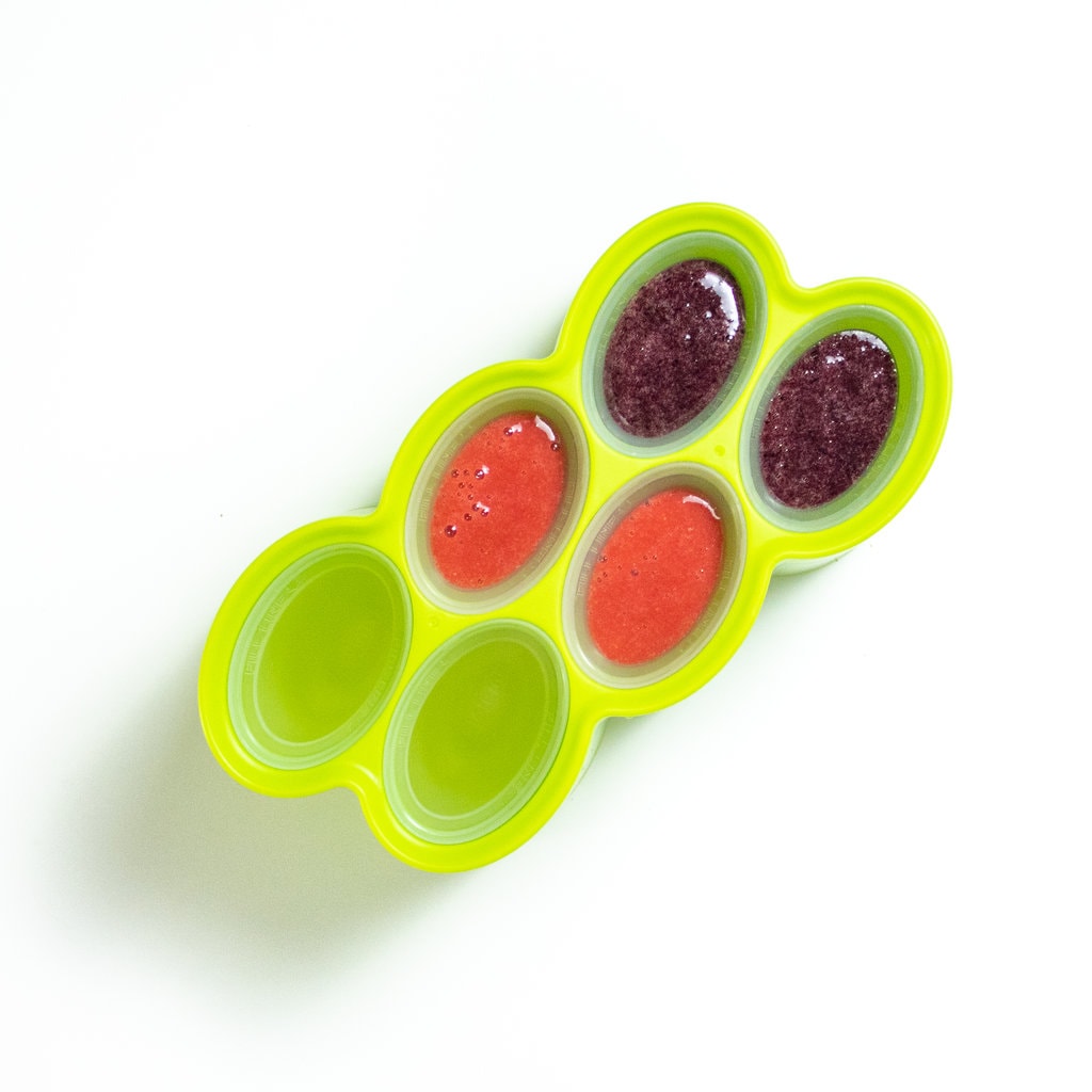 A green popsicle mold filled with 2 different flavors of popsicles.