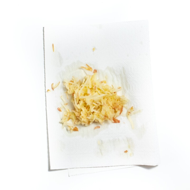 Paper towel on a white counter with shredded apple on top.