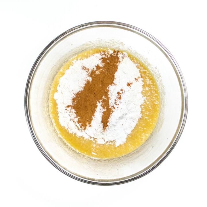 Clear bowl with both wet muffin ingredients and dry ingredients getting ready to mix together.
