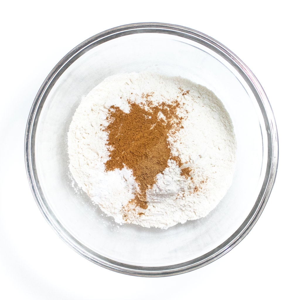 Clear glass bowl against a white background with dry ingredients for pancakes.