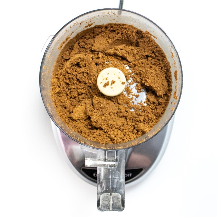 A food processor on a white countertop with ground up sunflower seeds.