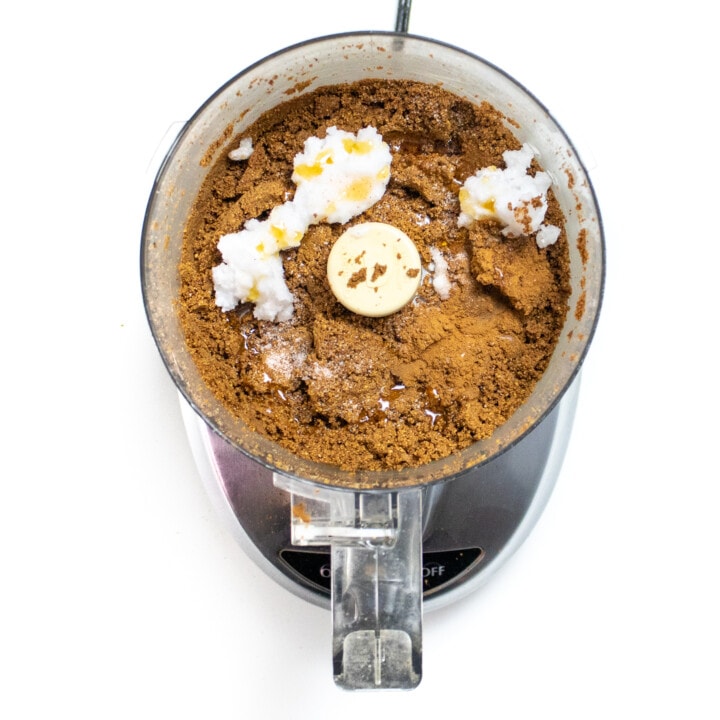 A food processor with ground up sunflower seeds, and additional ingredients to make some butter.