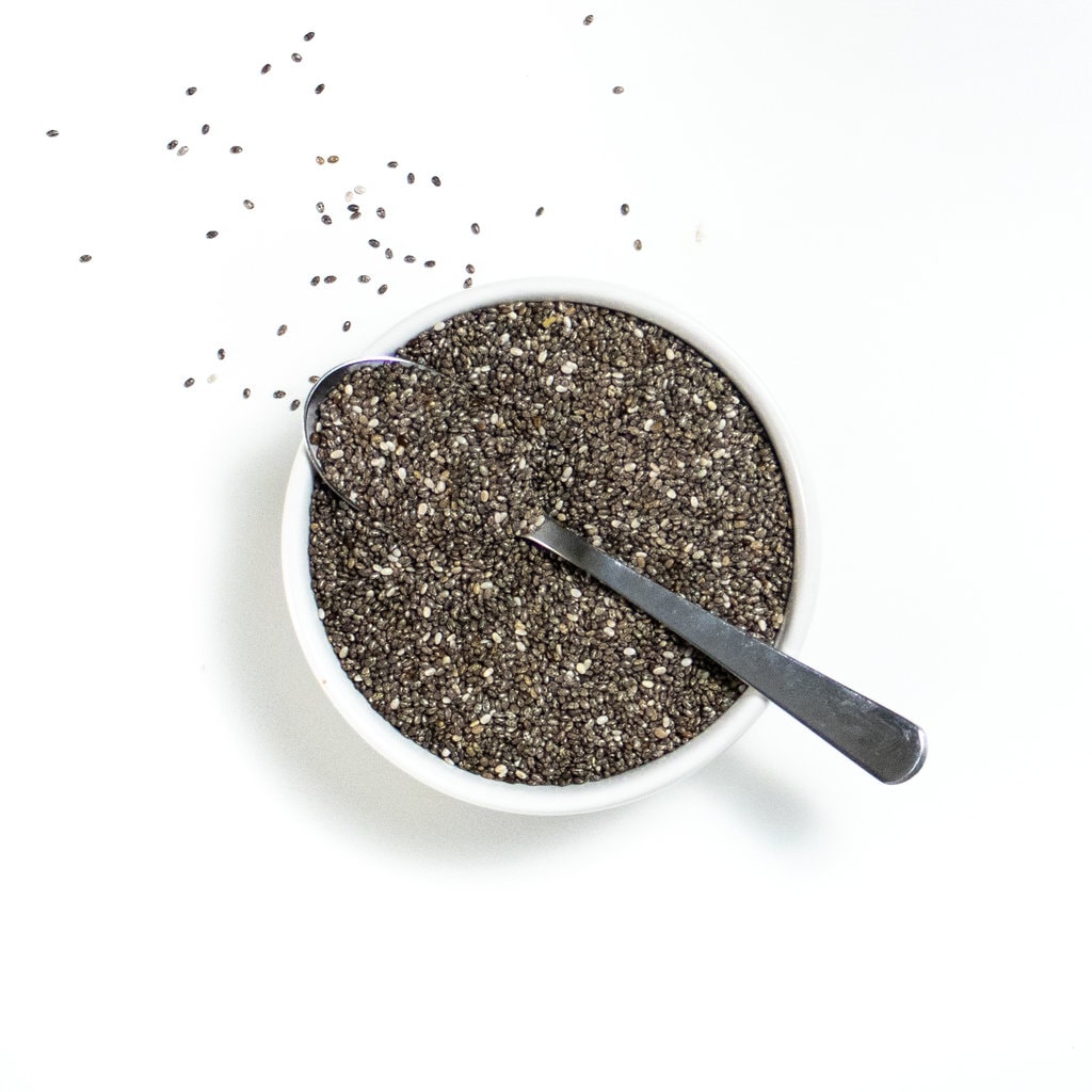 Small white bowl on white counter with a silver spoon resting on top.