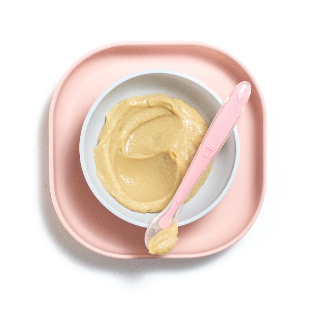 Pink baby plate and bowl with chickpea puree inside.