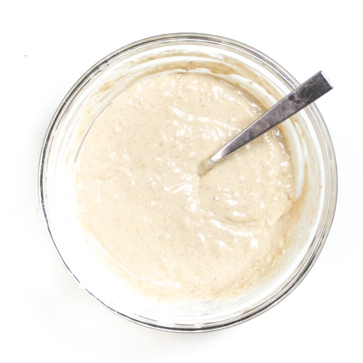 Clear glass bowl with a basic pancake batter sitting on a white counter.
