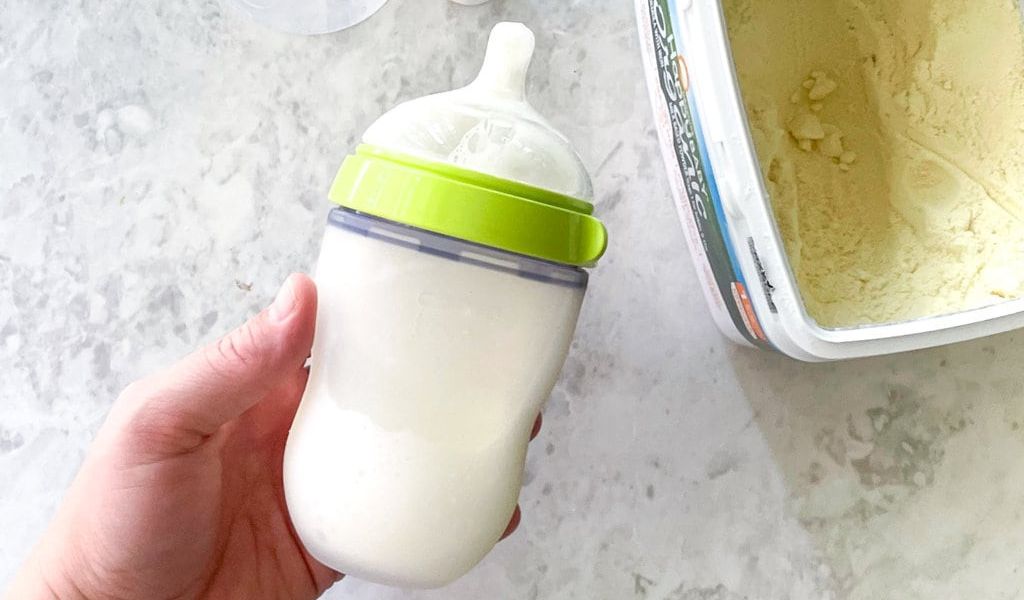 Holding Comotomo baby bottle next to formula