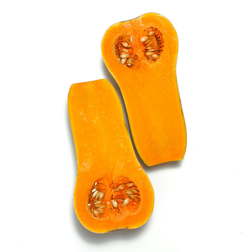 Two halves of a butternut squash on a white countertop.