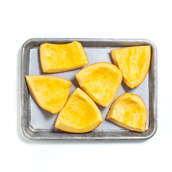 Silver baking sheet with chunks of cut and deseeded pumpkin.