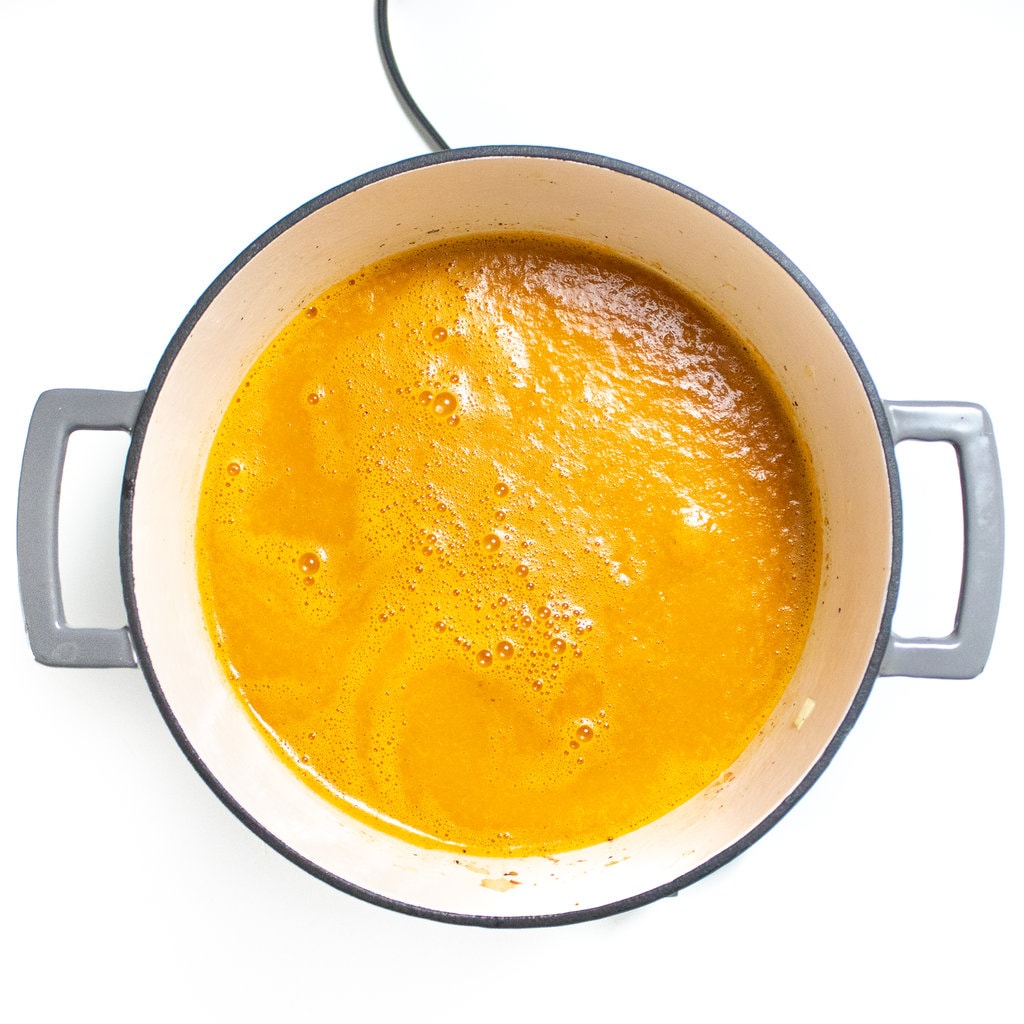 A blended base stock for alphabet soup in a large gray stockpot on the white countertop.