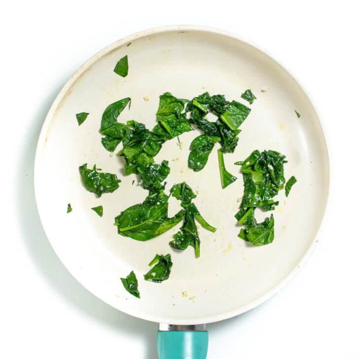 White skirt and a white countertop with sautéed spinach with garlic.