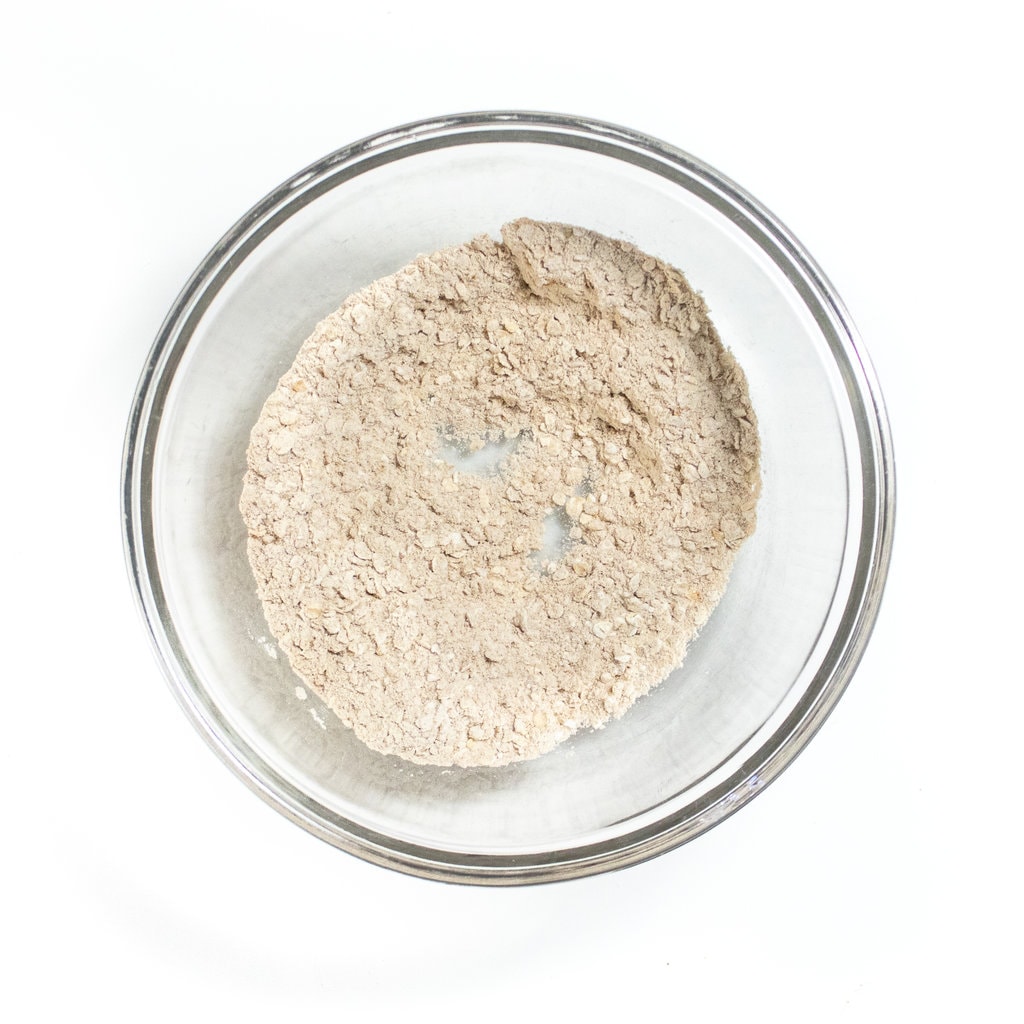 Clear bowl with dry ingredients for baby cookies against the white countertop.