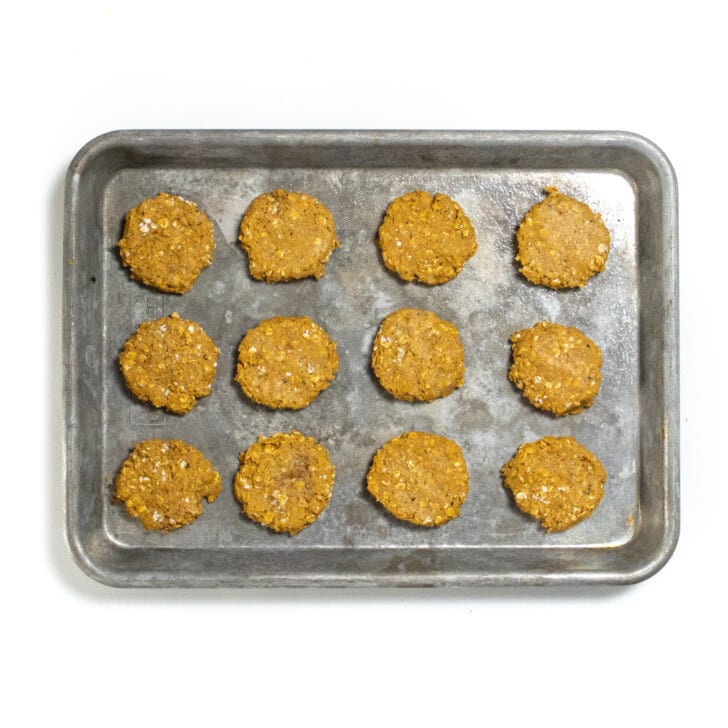 Small baking sheet with flattened baby cookies ready for the oven.