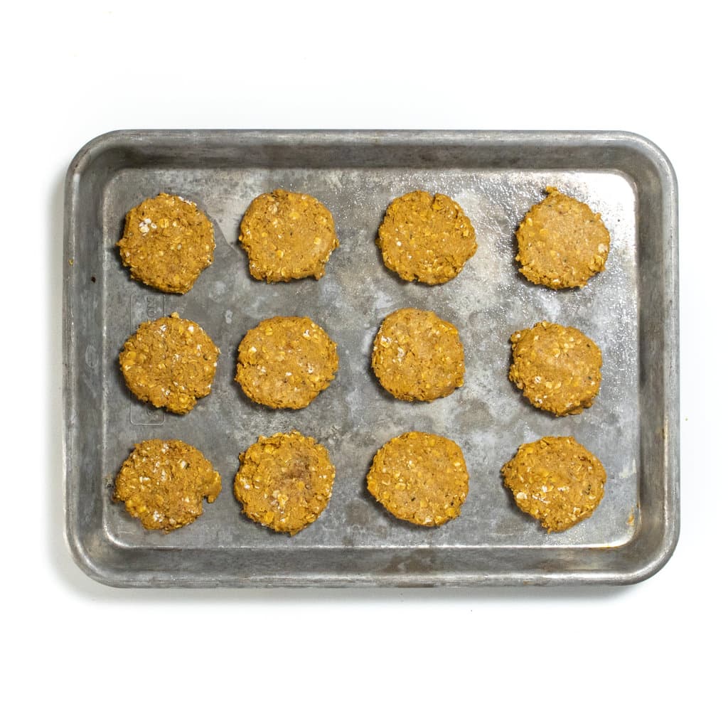 Small baking sheet with flattened baby cookies ready for the oven.