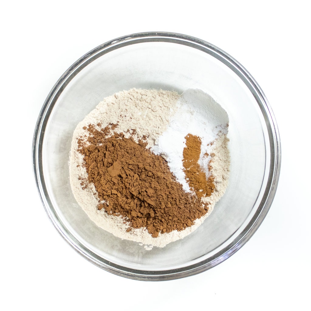 A clear mixing bowl with dry ingredients for chocolate pancakes.