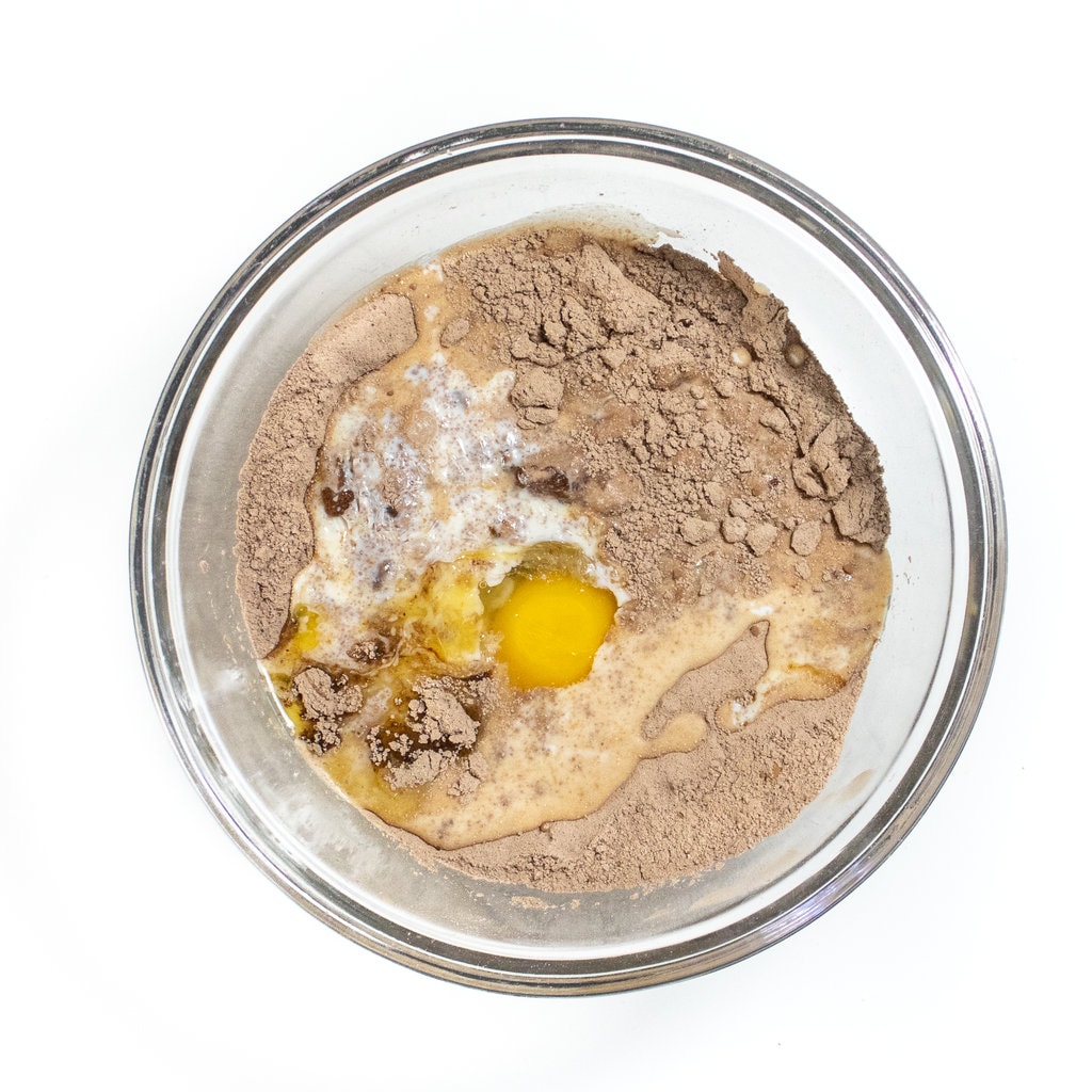 A clear mixing bowl with ingredients for pancakes with chocolate.