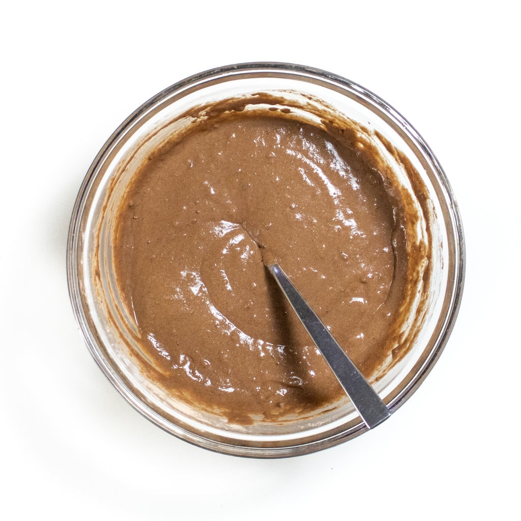 A glass mixing bowl with chocolate chip pancake batter inside.