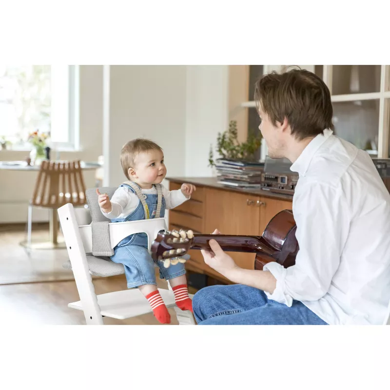dad and baby in a kitchen with the baby sitting in a tripp trapp high chair.