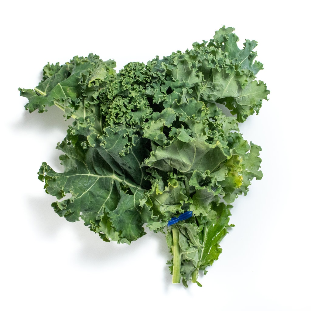 A bunch of kale sitting on a white countertop.