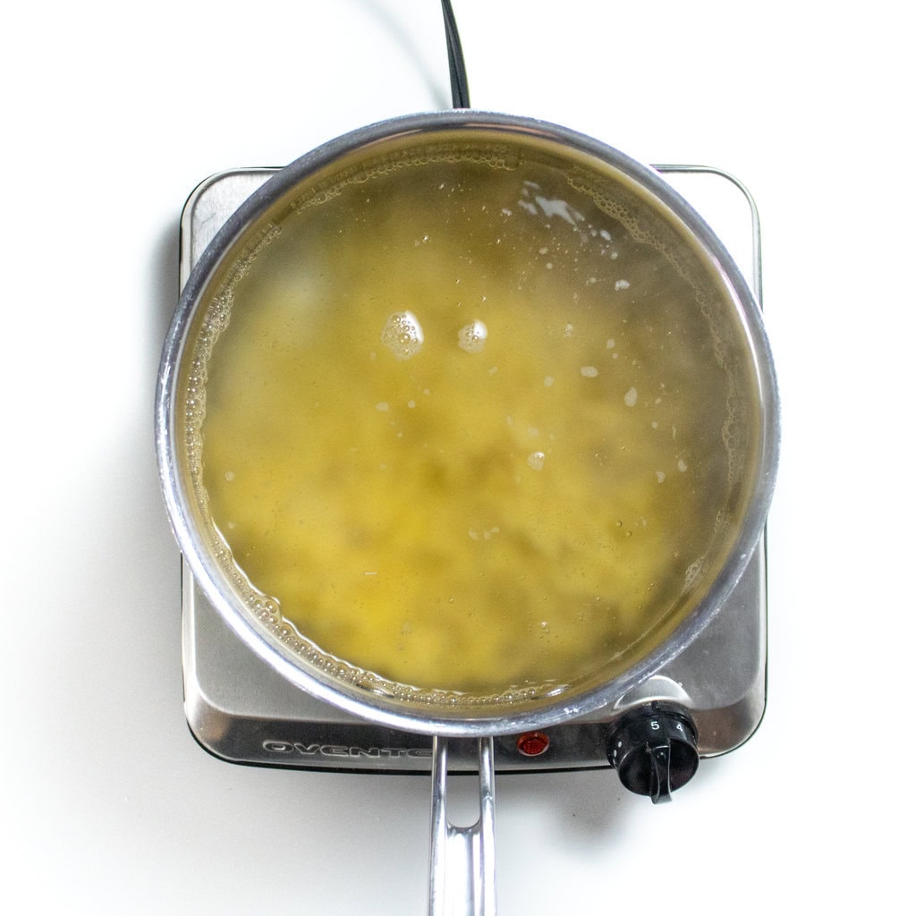 A silver sauce, pan with boiling water and pasta.